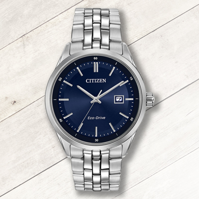 CITIZEN<sup>&reg;</sup>- Men's Eco Drive Watch-  Silver-tone with blue dial. The Stainless Steel case offers contemporary style while maintaining a timelessly classic appeal. Eco-Drive allows it to charge by any light source indoors or out and will never need a battery. Features a fold-over safety clasp with a sapphire crystal and water resistant to 100M.